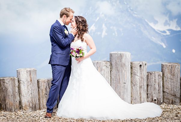 Braut und Bräutigam stehen mit Gesicht zueinander vor Bergkulisse