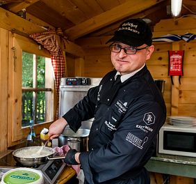 Koch steht in kleiner Hütte an einem Herd