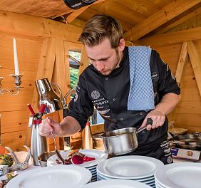 Koch verteilt Sauce auf einem Teller