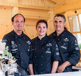 Zwei Köche und eine Köchin lächeln in die Kamera