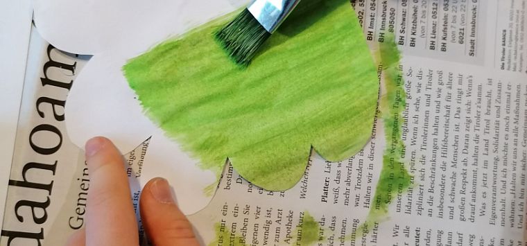 Hand mit Pinsel bemahlt den Baum grün