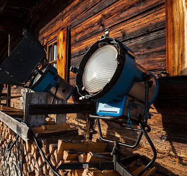 Große Scheinwerfer-Lampen stehen vor Holzhütte