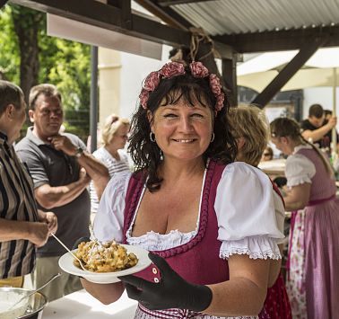 Frau in Dirndl hält Teller mit Kaiserschmarrn in der Hand