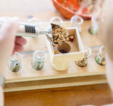 Blick von oben auf eine Hand, die Getreide in Gläser füllt