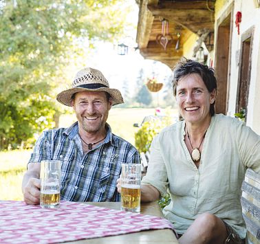 Mann und Frau sitzen auf am Tisch vor dem Haus