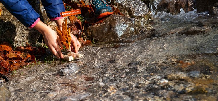 Nahaufnahme einer Hand, die das Korkschiff ins Wasser setzt