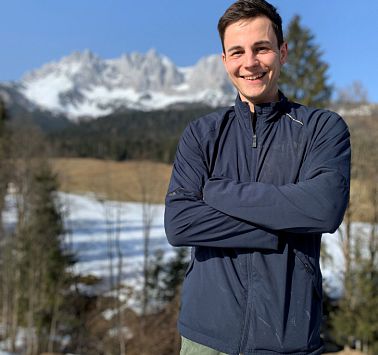 Junger Mann mit verschränkt lächelnd die Arme