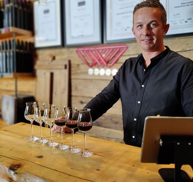 Mann steht an Theke mit gefüllten Schnapsgläsern