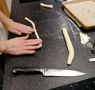 Hände formen den Teig zu einer Schlange