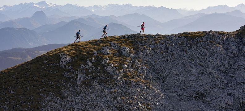 Drei Männer beim Trailrunning auf einem Bergkamm in der Region Wilder Kaiser. Im Hintergrund ein gigantisches Bergpanorma