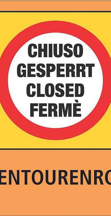 Schild mit gelbem Hintergrund: "Pistentourenroute gesperrt" in mehreren Sprachen. Warnsignal innen in Rot-Weiß. Sicherheitsinformation für Skifahrer.