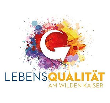 Colorful logo for "Lebensqualität am Wilden Kaiser" with splashes of paint around a stylized G. It emphasizes vibrant living in the Wilder Kaiser region.