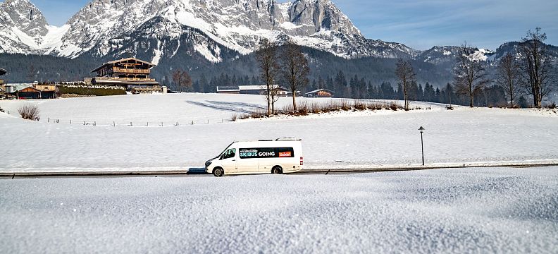 Skibus auf schneebedeckter Straße vor dem Kaisergebirge in Going am Wilden Kaiser.