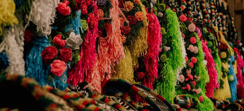 Bunte, reich mit Blumen verzierte Kuhglocken hängen in einer Reihe. Die Vielfalt der Farben und Details spiegelt traditionelle alpine Handwerkskunst wider.