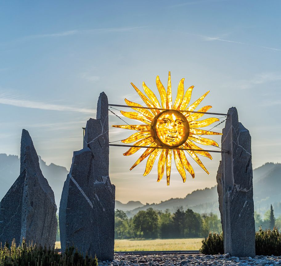 Faszinierende Sonnenskulptur vor dem beeindruckenden Panorama des Wilden Kaisers, beleuchtet vom warmen Licht eines Sonnenauf- oder -untergangs.