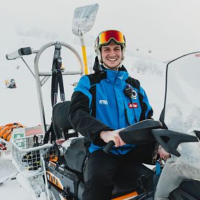 A SkiWelt employee is sitting on a Ski-Doo and laughing.