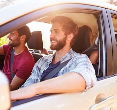 Vier Insassen schauen bei heruntergekurbelten Fenstern aus Auto