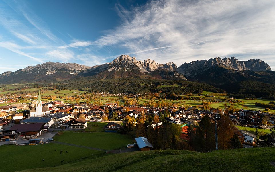 Stunning sunrise over the Wilder Kaiser mountains in Tyrol, Austria, illuminating the rocky peaks and surrounding valleys with a warm, golden light.