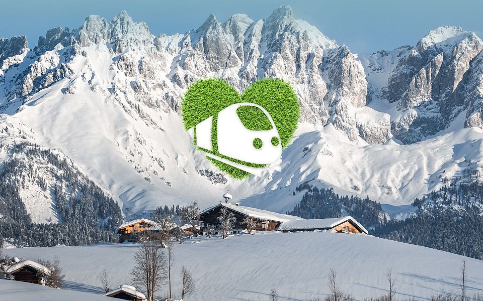 Snow-covered Wilder Kaiser mountains with alpine huts nestled below, showcasing a picturesque winter landscape in the Tyrol region.