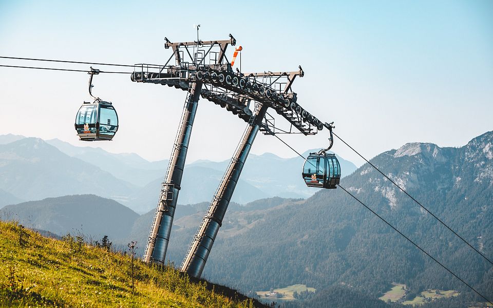 Cable car in Wilder Kaiser with stunning mountain backdrop and clear blue sky, perfect for alpine adventures.