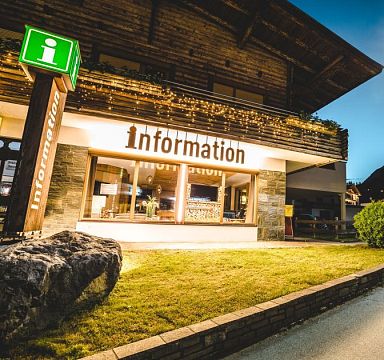 Beleuchtetes Gebäude mit Infosäule und Aufschrift "Information"