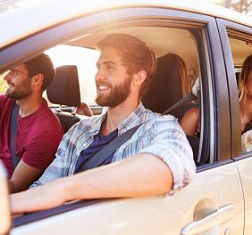 Vier Insassen schauen bei heruntergekurbelten Fenstern aus Auto