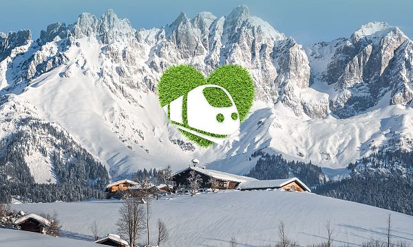 Snow-covered Wilder Kaiser mountains with alpine huts nestled below, showcasing a picturesque winter landscape in the Tyrol region.
