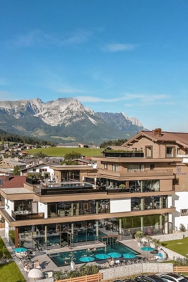 Village in Wilder Kaiser region, featuring traditional Alpine buildings and a stunning mountain range in the background.