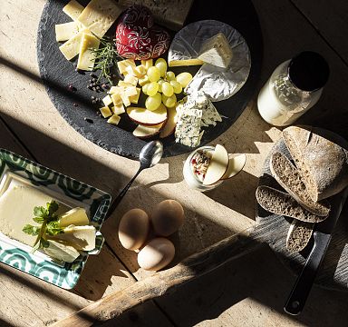A rustic cheese and bread platter with grapes, eggs, and butter in natural light, showcasing regional delicacies from the Wilder Kaiser area.