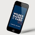 Ein Smartphone zeigt die "Wilder Kaiser Card" mit den Wörtern "Fahrkarte" und "Bus Ticket" auf blauem Hintergrund.