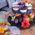 A breakfast spread featuring fruits, jams, and a drink on a table with colorful flowers, evoking a traditional Tyrolean setting under the majestic Wilder Kaiser.