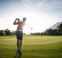 Golfer beim Abschlag in Richtung Sonne