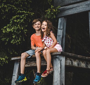 Junge und Mädchen sitzen auf übergroßen Holzstuhl