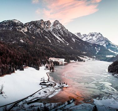 Blick auf zugefrorenen Gebirgssee und schneebedeckte Berggipfel