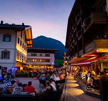 Menschen sitzen auf Restaurant-Terrassen und hören der Musik