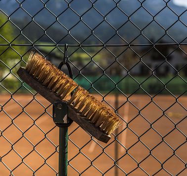 Maschendrahtzaun mit befestigtem Besen vor Gebirgszug