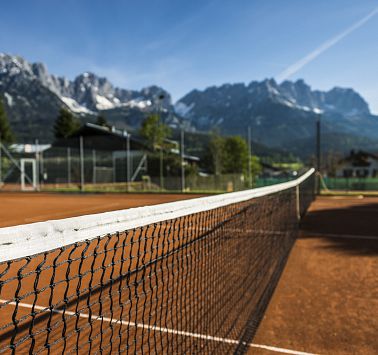 Netz über Tennisplatz vor Bergkulisse im Sonnenschein